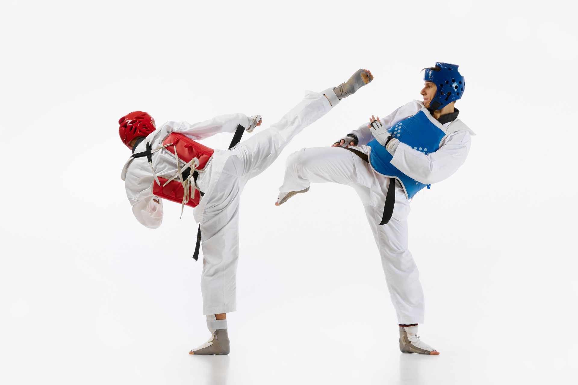 Athletic, motivated young men, taekwondo athletes in motion, practicing, training isolated over white background. Martial arts, combat sport